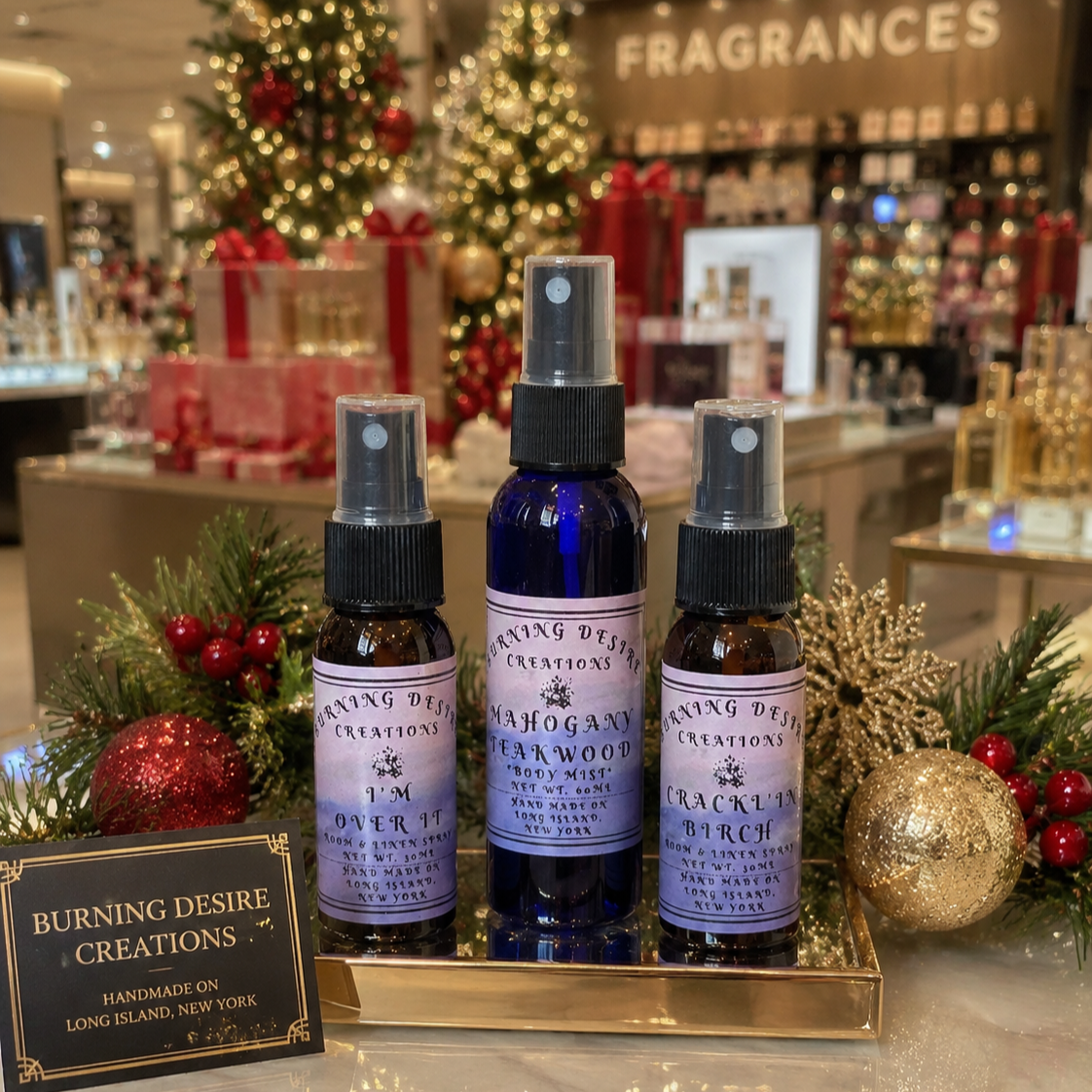 Three Burning Desire fragrance spray bottles displayed with holiday decorations.